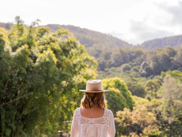 a woman standing backwards overlooking the verdant landscape at Eden Health Retreat