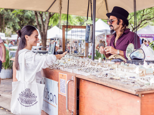 a woman talking to a stall vendor at Eumundi Markets