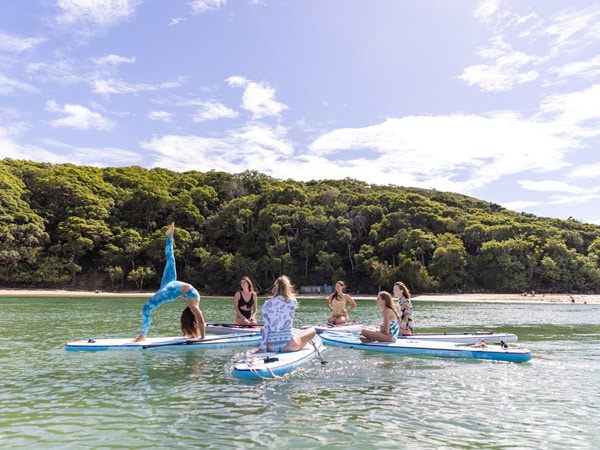 a group of women taking a yoga class while riding a paddleboard
