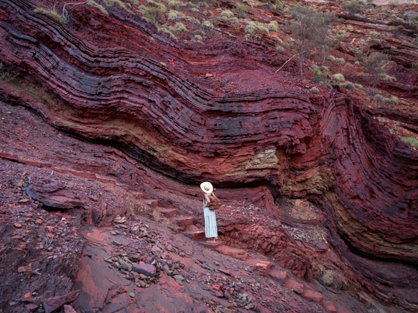 a woman admiring the striking red rock formations at Karijini National Park