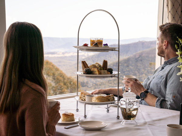 a couple looking out the panoramic view of Megalong Valley while enjoying high tea at Hydro Majestic Blue Mountains