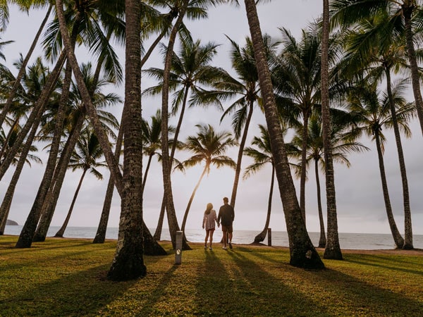 Couple standing at Palm Cove beach at sunset. (Image: Tourism and Events Queensland)