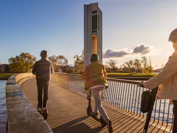three teenagers riding a scooter around Lake Burley Griffin and National Carillion