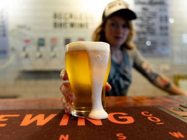 a woman holding an overflowing glass of beer on tap at Reckless Brewing, Bathurst
