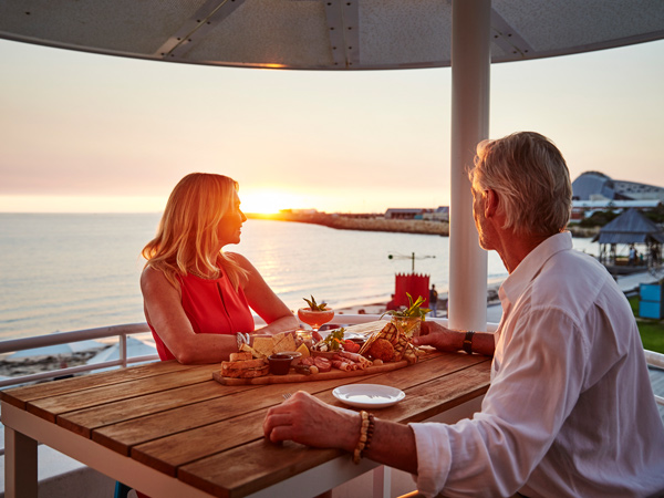 a couple enjoying drinks set against panoramic sea views at Bathers Beach House, Perth