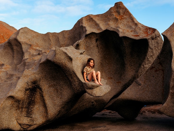 Child sits on Remarkable Rocks on Kangaroo Island