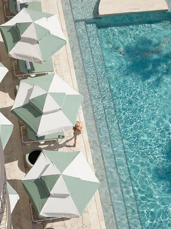A woman in a swimsuit walking along a pool.