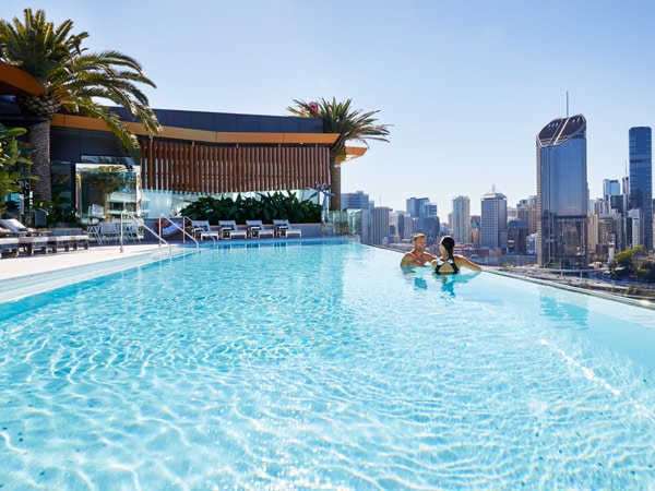 Two people in a swimming pool talking.