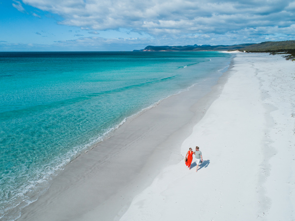 an aerial view of a couple walking along Friendly Beaches, Tasmania