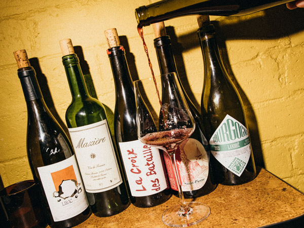 pouring wine into a glass in front of wine bottles at Casa Wine Bar, Perth