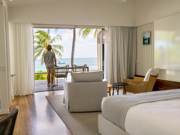 a man looking out the window of his suite at Lizard Island Resort