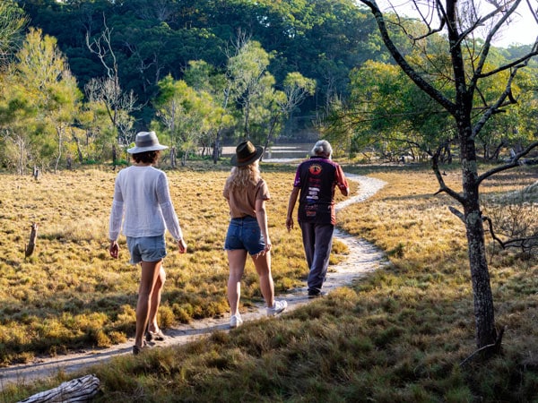 three people walking along a rainforest trail at Jellurgal Aboriginal Cultural Centre, Burleigh Heads Queensland