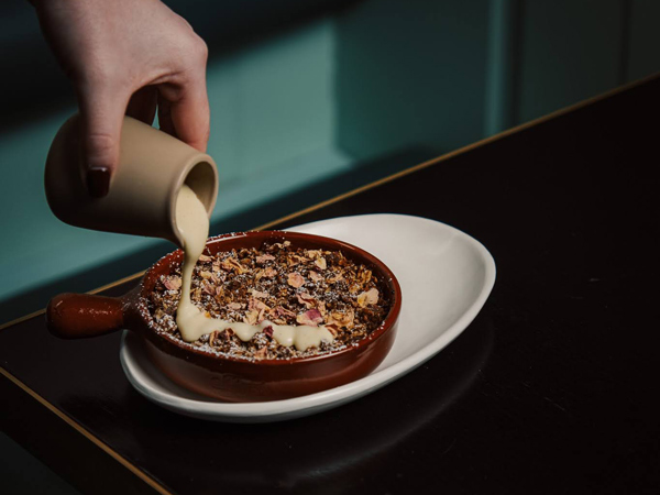 pouring sauce on top of a dish at Corella Restaurant in Braddon