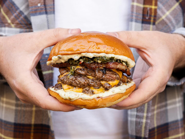 a hand holding a burger at Grease Monkey, Braddon