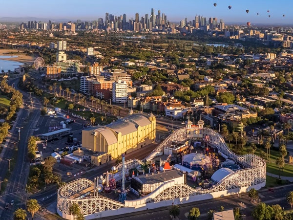 an aerial view of Luna Park in St Kilda with city skyline and balloons