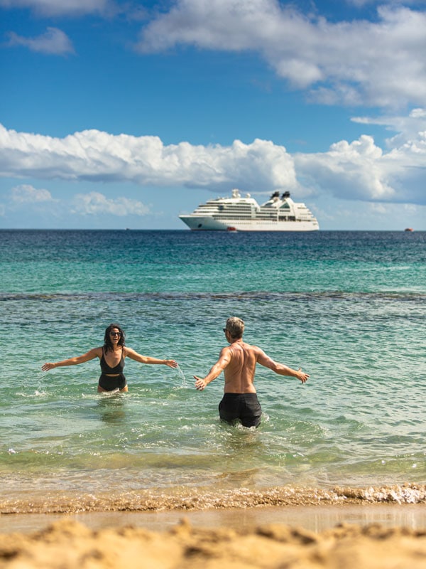 a couple enjoying at sea with Seabourn Odyssey cruise ship on the background