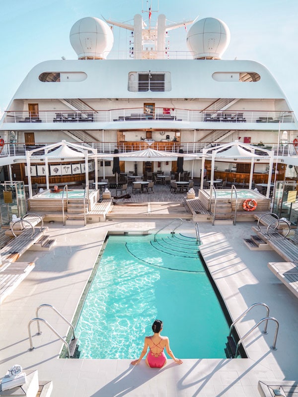 an overhead shot of a woman sitting on the side of the pool at Seabourn cruise ship, Australia