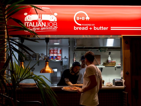 a guy holding pizza in front of The Collective Palm Beach