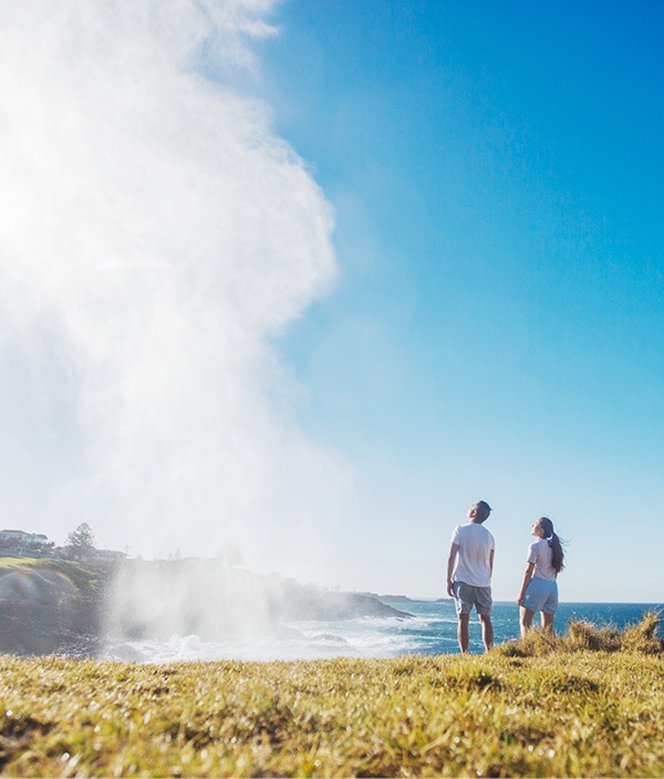 Two people standing on cliff looking out to sea