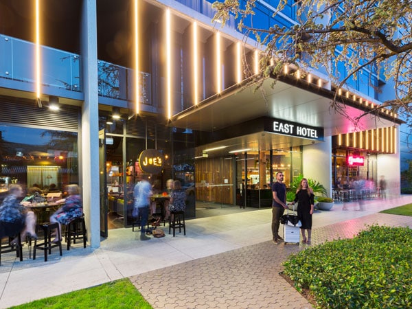 a couple posing for a photo outside East Hotel Canberra