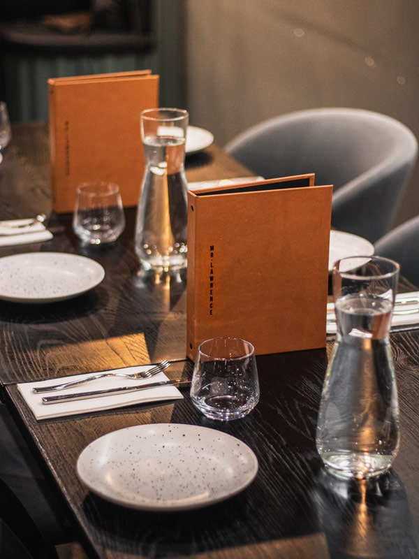 A table is set with orange menus that say Mr. Lawrence on them. (Image: Mr. Lawrence)