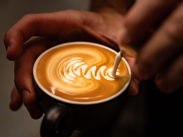 a hand pouring milk over coffee at Trail St Coffee Shop, Wagga Wagga