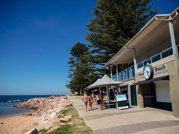 Visitors pass the Point Cafe at Avoca Beach on the Central Coast.