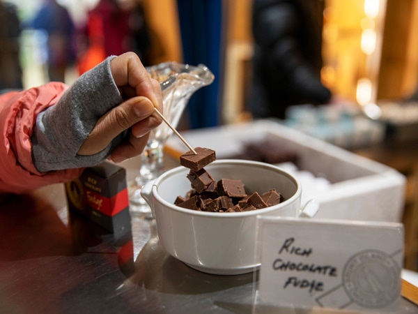 a hand skewing a bite-sized chocolate in a bowl using a toothpick