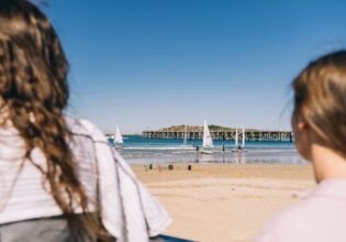 two women standing on jetty beach coffs harbour