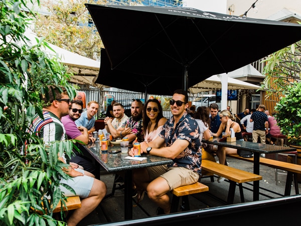Group sits in the beer garden at the Pig N Whistle in Brisbane, QLD