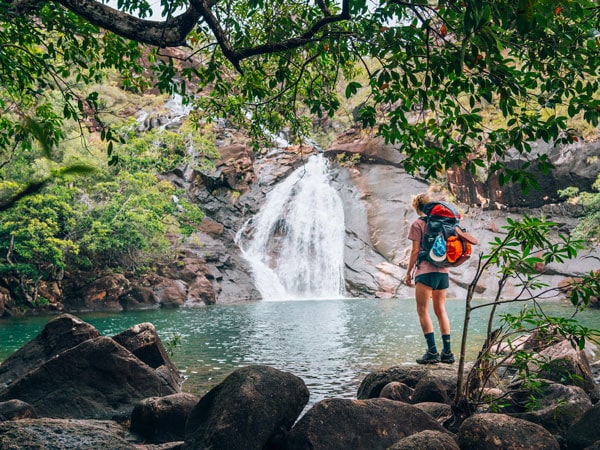 a hiker stopping by a waterfall at Thorsborne Trail