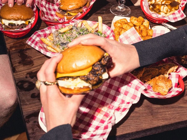 a hand holding a burger at Leonard’s House of Love, South Yarra