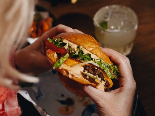 a hand holding a burger at Lulie Tavern, Abbotsford