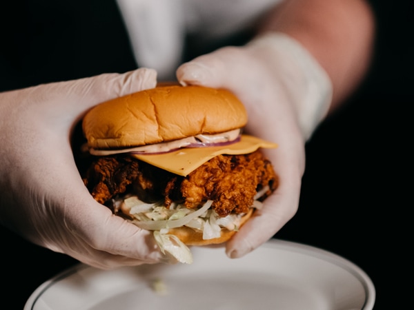 a hand holding Mabels' burger up close