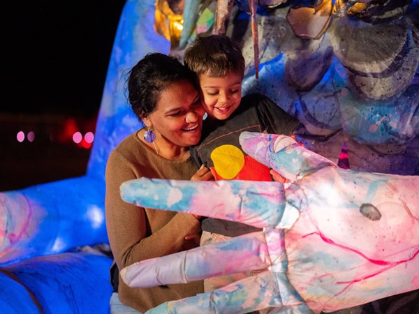 A mother and son experience the Arelhe Urrperle Erth Puppet at Parrtjima 2024