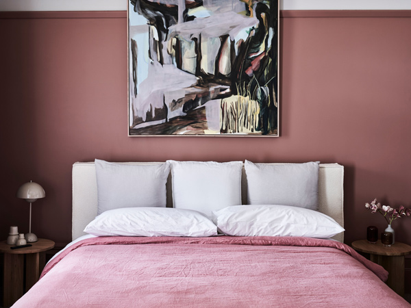 a pink bed with a painting hanging on the wall at Hotel Vera, Ballarat