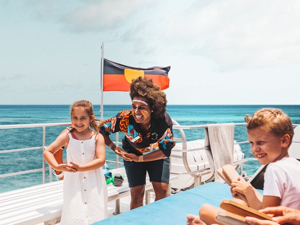 an indigenous guide teaching traditional dance to children on board Dreamtime Dive & Snorkel