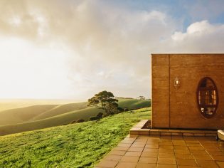 The Sky House on Kangaroo Island, atop a grassy hill with sun shining.