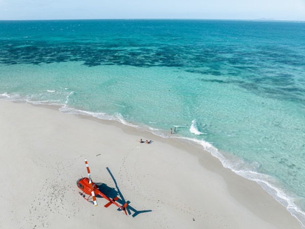 an aerial view of a helicopter touching down a beach in Cairns, Nautilus Aviation