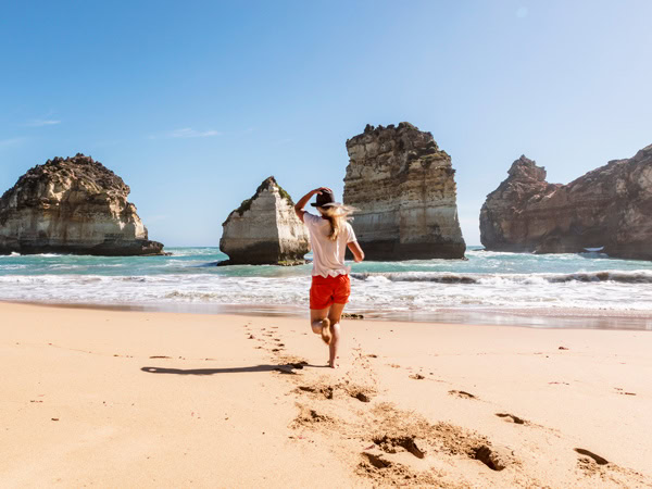 a person walking with trail of barefeet on the sandy beach at Childers Cove