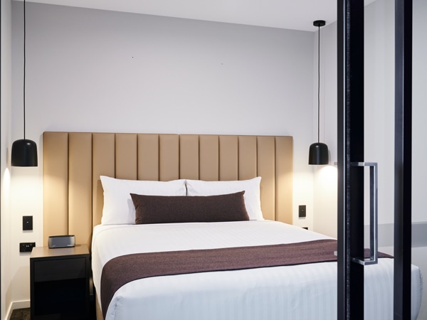 a queen bed inside the two-bedroom apartment at Abode Hotel Canberra