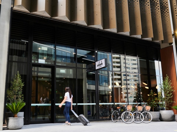 a woman pulling her luggage as she enters Abode Belconnen