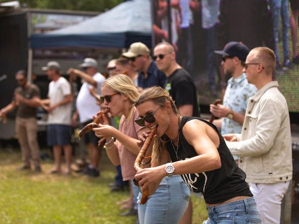 people eating huge sausage at the Craft Beer & BBQ Festival