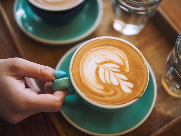 a hand holding a cup of cafe latte in Bay Blue Espresso Bar, Mount Gambier