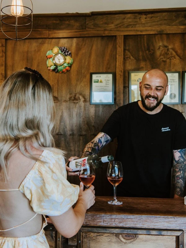 a bartender pouring wine into a glass in front of a woman at Naked Lady Wines, Mudgee