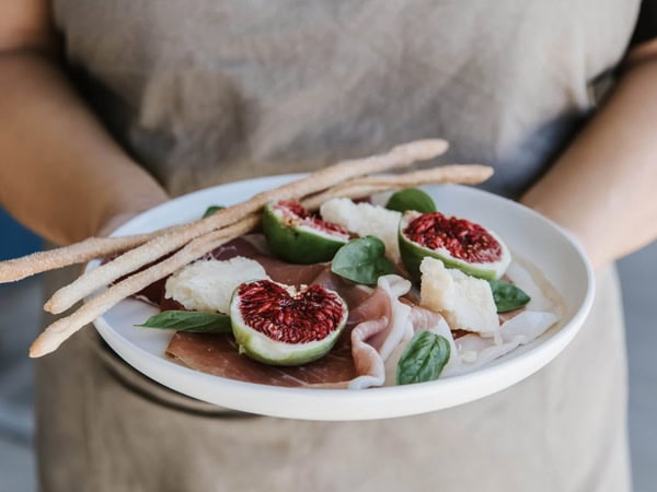 a woman holding a plate of Prosciutto & Fig recipe at The Barn at Blue Wren Farm
