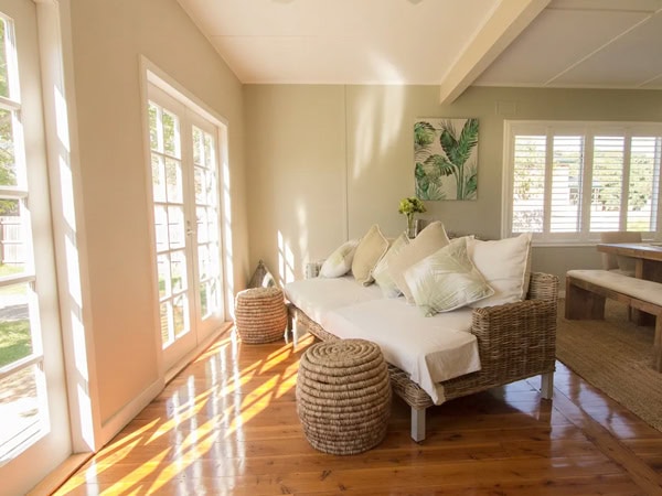 a couch facing the windows with sunlight casting through at Wine Lover's Den, Mudgee