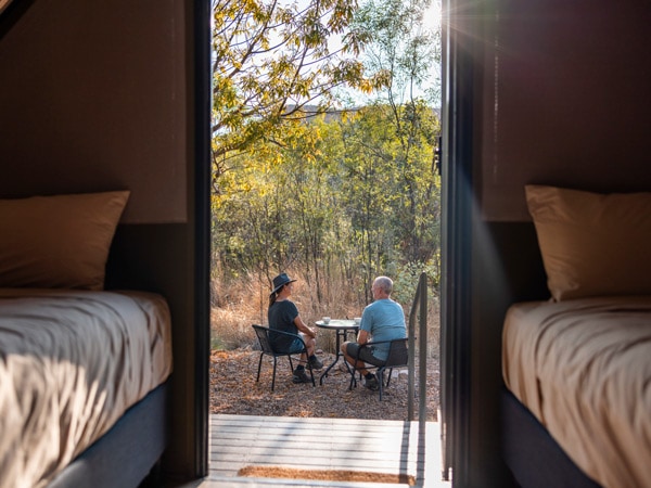 a couple sipping their morning coffee outside their tent at El Questro Wilderness Park, East Kimberley