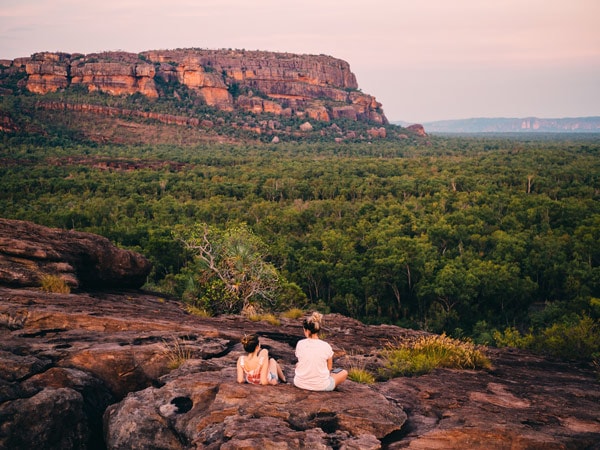 two people sitting on a rock at Nawurlandja Lookout, Kakadu
