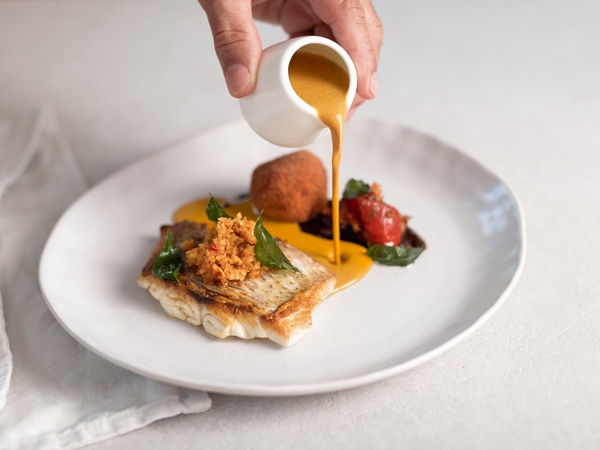a hand pouring sauce into a dish at ALBA by Kuruvita Food